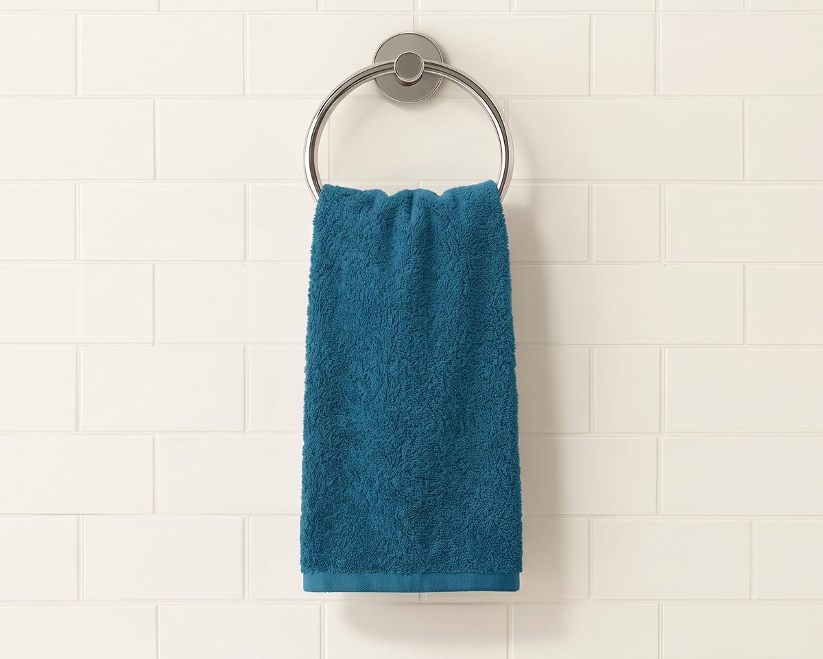 A teal blue towel hanging from a round silver metal ring on a white subway tile wall.